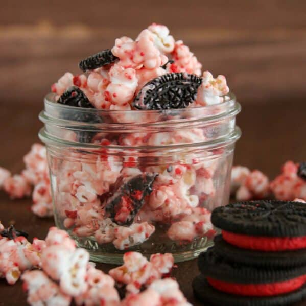 Small jar filled with peppermint popcorn with chunks of oreo cookies in it.
