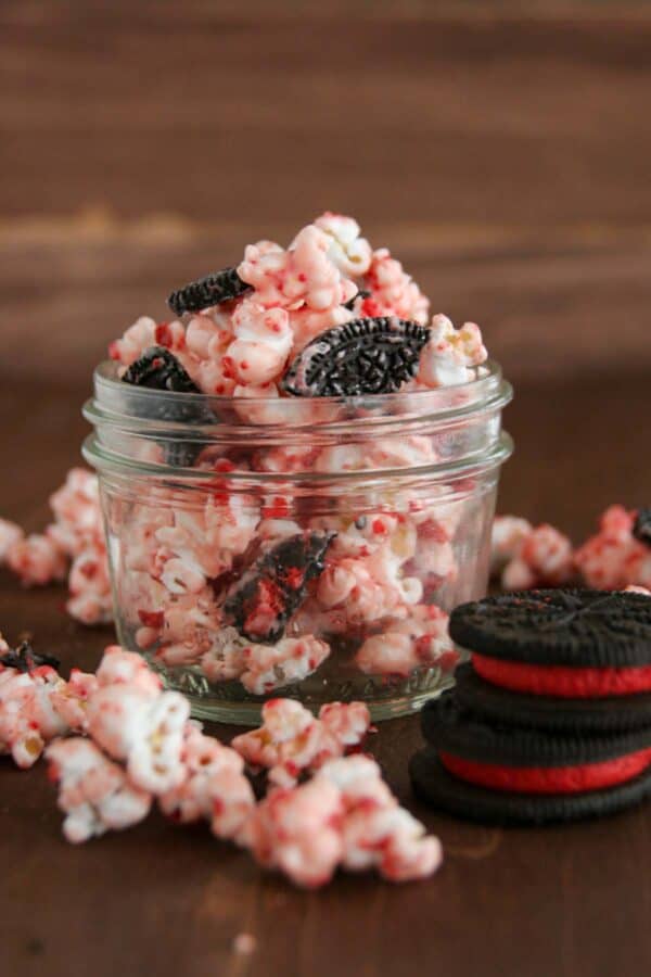 Small jar filled with peppermint popcorn with chunks of oreo cookies in it.