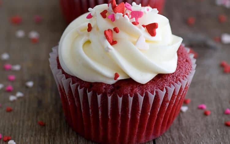 Red velvet cupcake topped with marshmallow cream cheese icing and sprinkles.