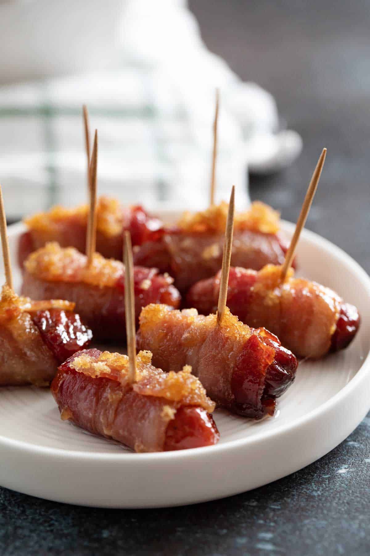 Bacon Wrapped Smokies with toothpicks on a plate.