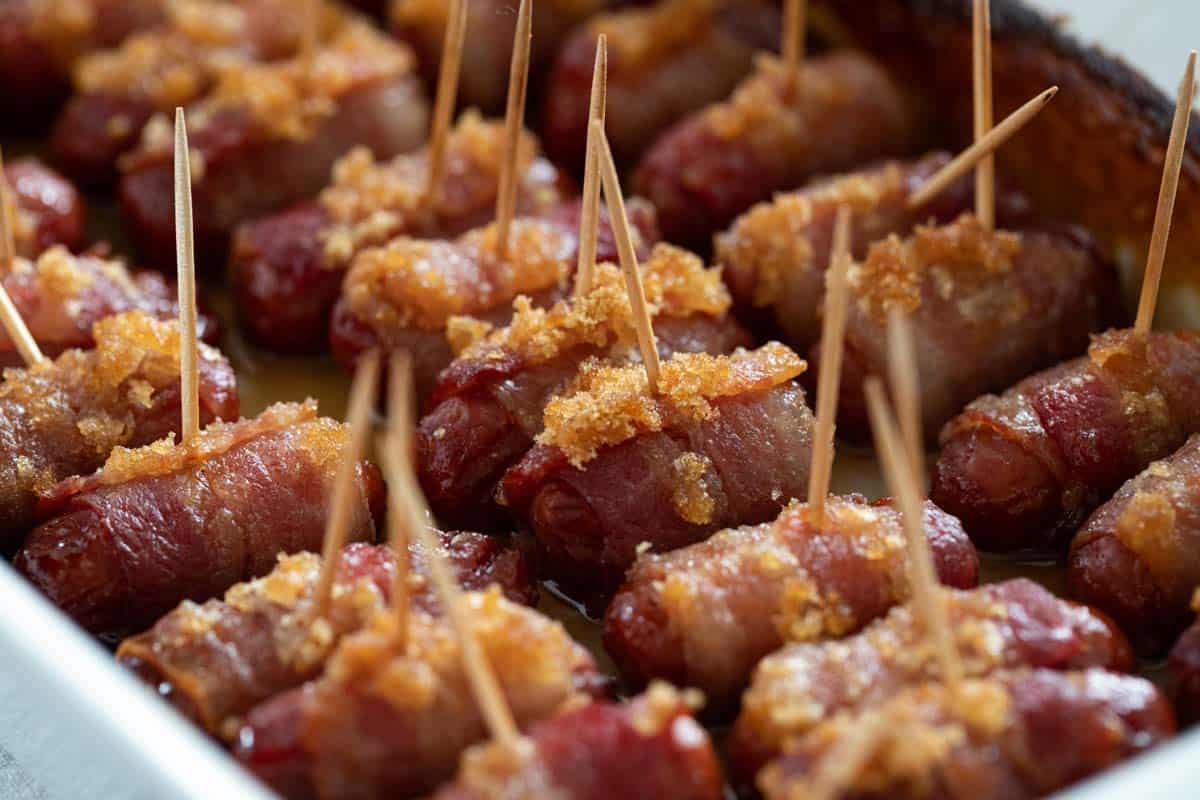 Bacon wrapped smokies with brown sugar in a baking dish.