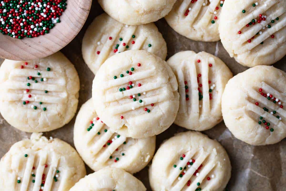 Buttery and melt in your mouth, these easy Christmas Shortbread Cookies are a cooke plate staple! Christmas Shortbread Cookies topped with red, green, and white sprinkles.
