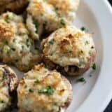 Crab stuffed mushrooms sprinkled with parsley on a plate.