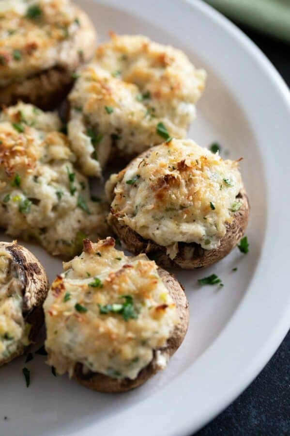 Crab stuffed mushrooms sprinkled with parsley on a plate.