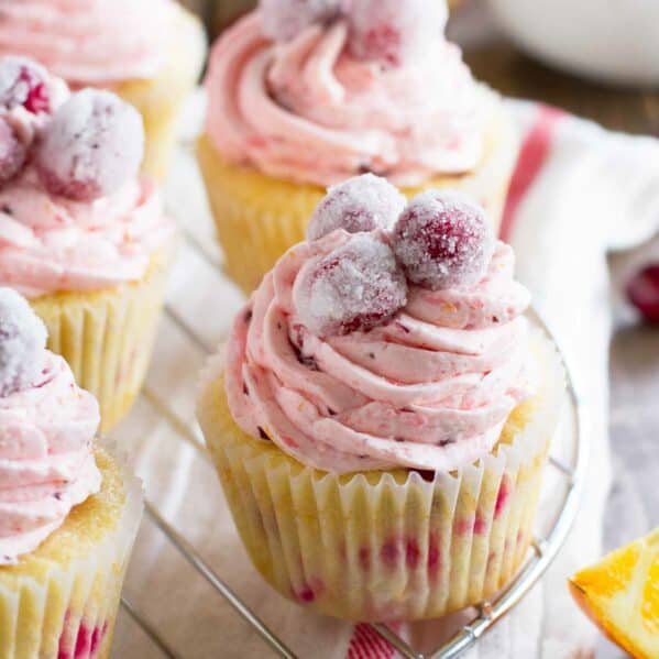 Cranberry Orange Cupcakes on a wire rack, topped with sugared cranberries.