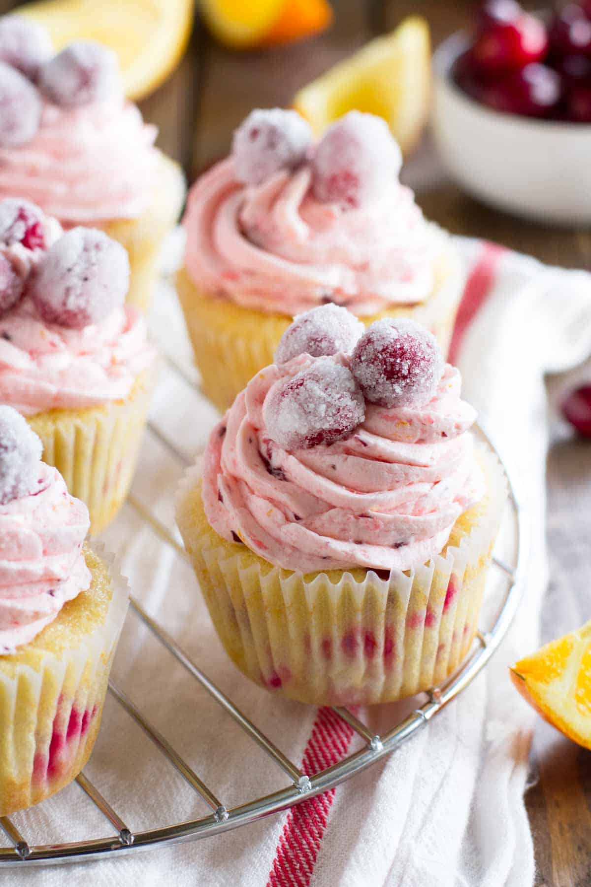 Cranberry Orange Cupcakes on a wire rack, topped with sugared cranberries.