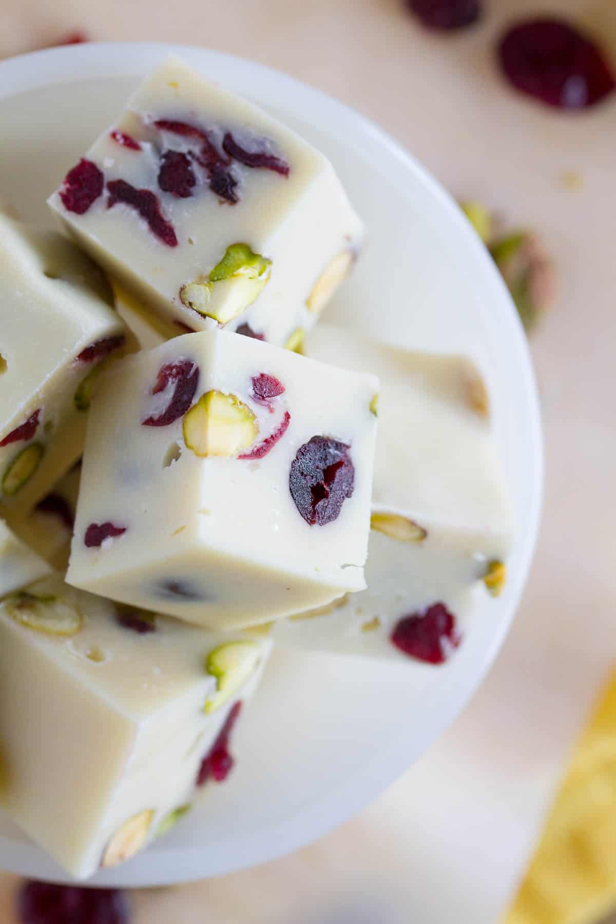 Fudge doesn’t have to be complicated or intimidating! This easy Creamy Cranberry Pistachio Fudge only takes minutes of hands on time, no candy thermometer, and only has 6 ingredients! slices of cranberry pistachio fudge, showing texture and nuts and fruit.