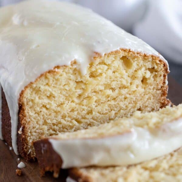 Loaf of eggnog bread with eggnog bread sliced on a cutting board.