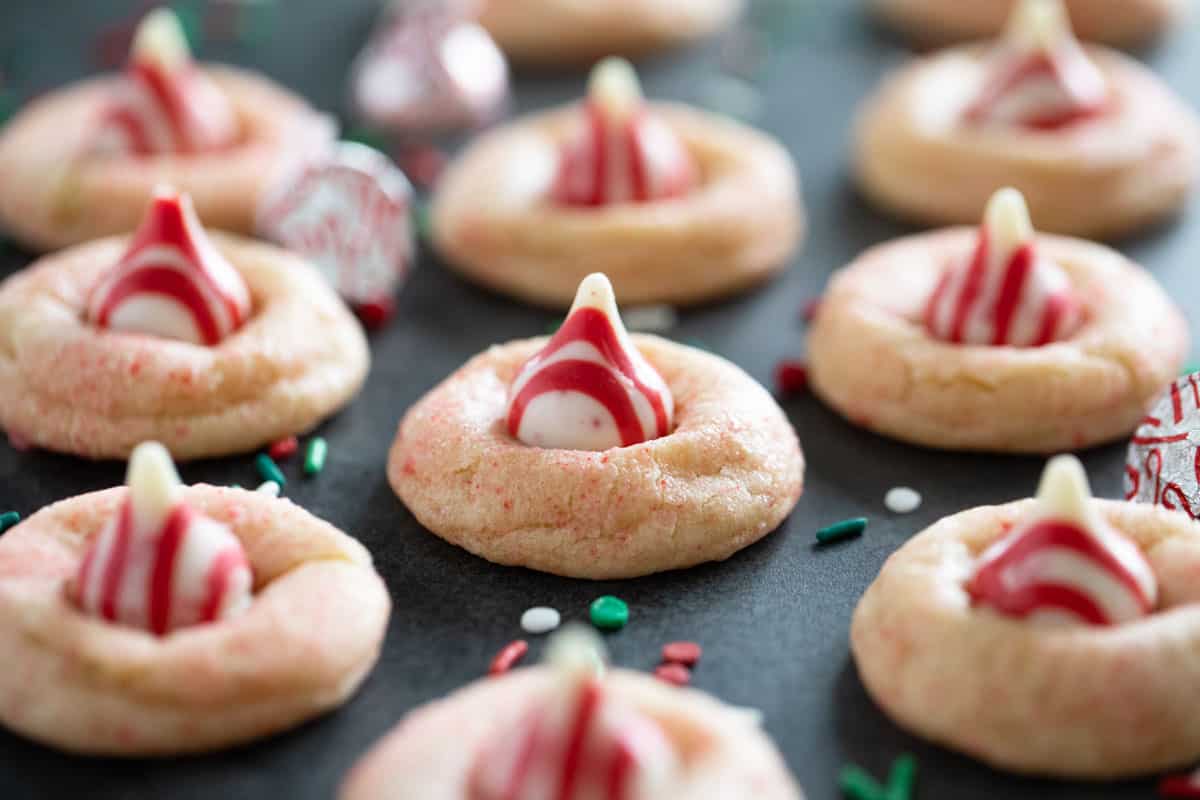 Peppermint Kiss Cookies surrounded by sprinkles and kisses.