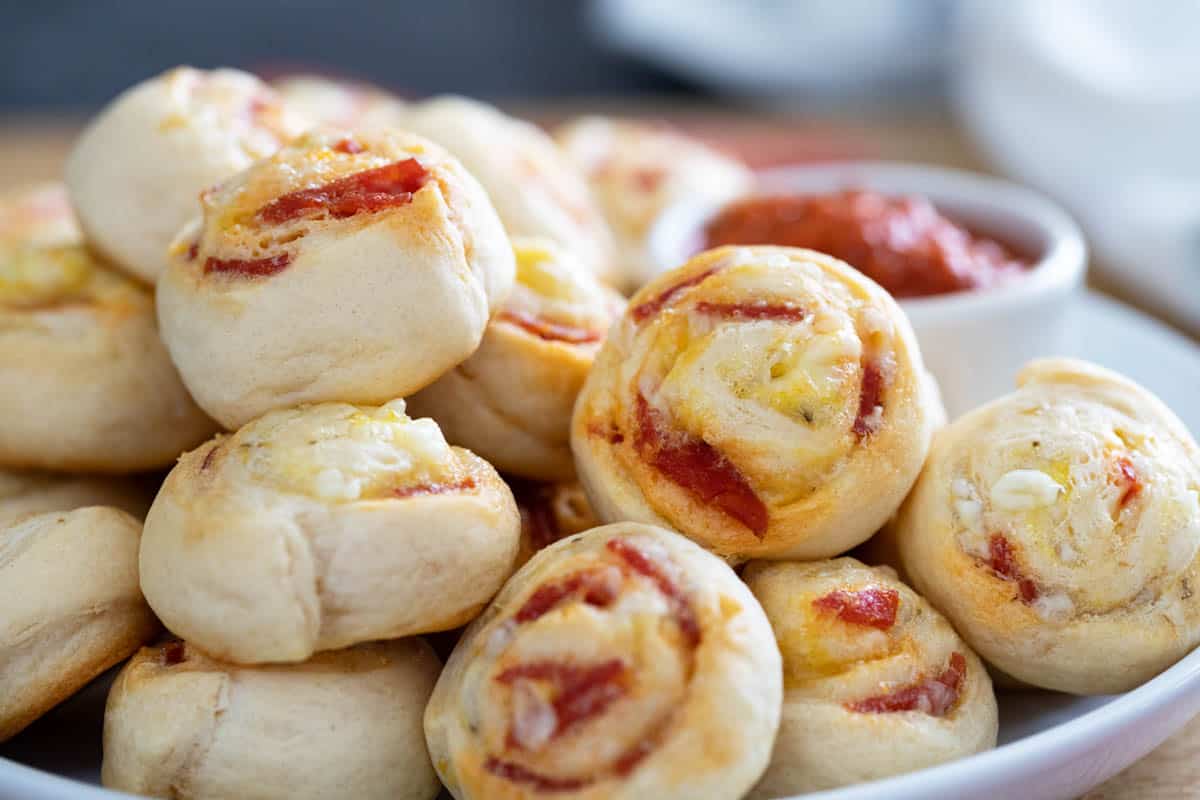 Pepperoni Pinwheels stacked on a plate with dipping sauce.