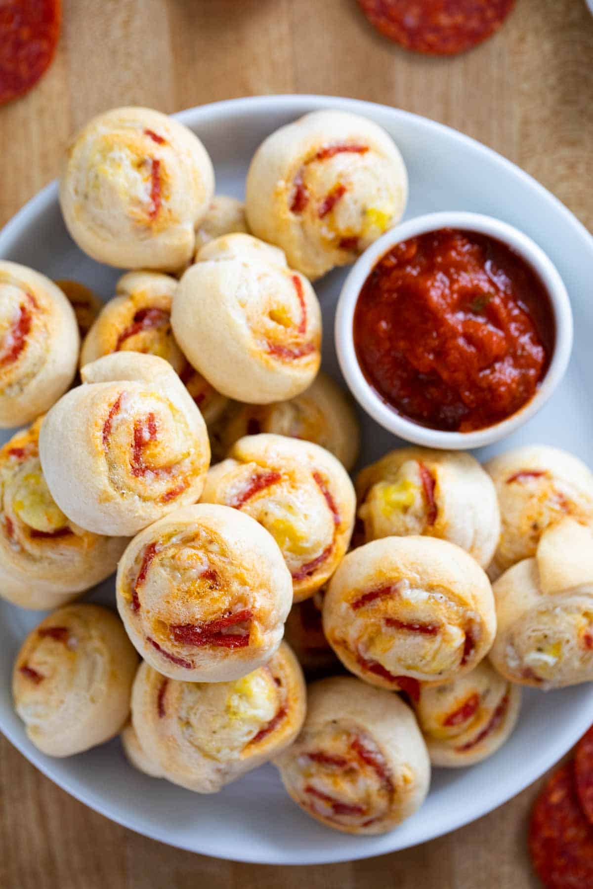 Pepperoni Pinwheels on a plate with a small bowl of marinara sauce for dipping.