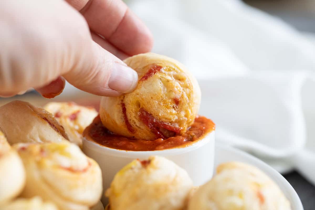 Dipping pepperoni pinwheel into marinara sauce.