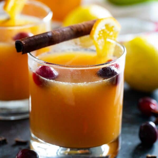 Glass filled with wassail and topped with orange slices and cranberries.