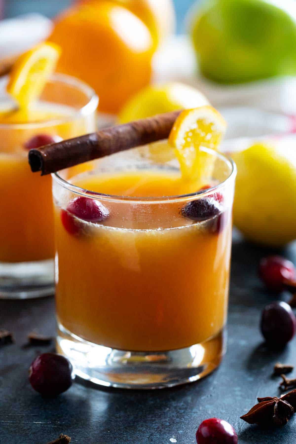 Glass filled with wassail and topped with orange slices and cranberries.