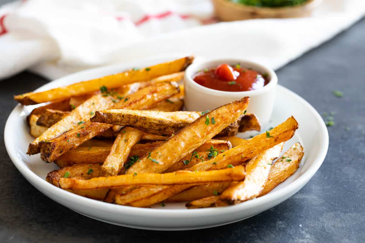 Plate with baked French fries and ketchup.