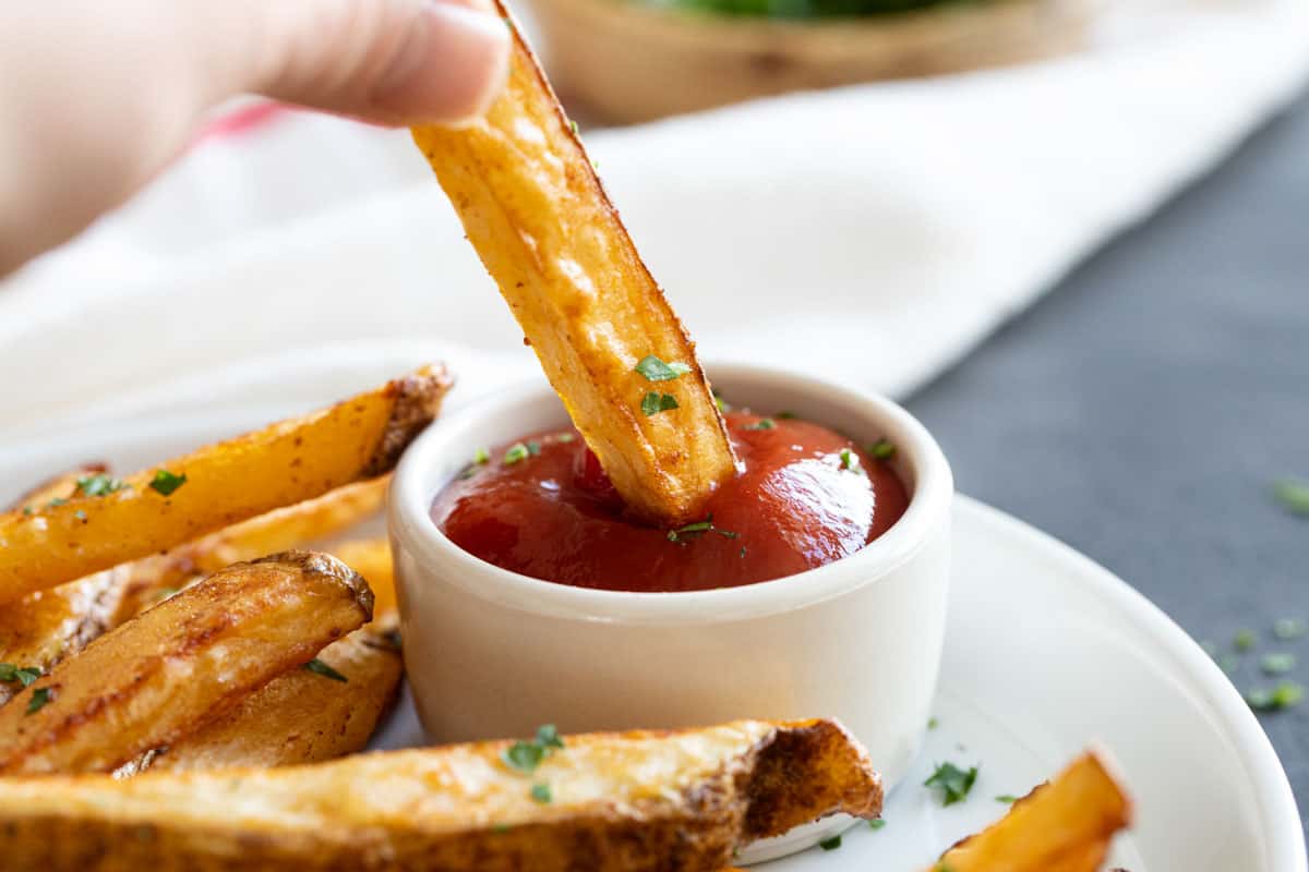 Dipping a baked French fry into ketchup.