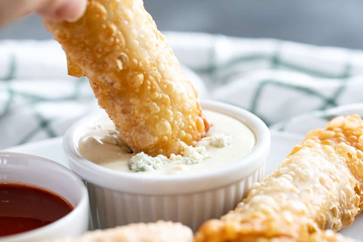 Dipping a buffalo chicken egg roll into blue cheese dressing.