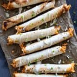 Buffalo Chicken Taquitos drizzled with blue cheese dressing and sliced green onions.