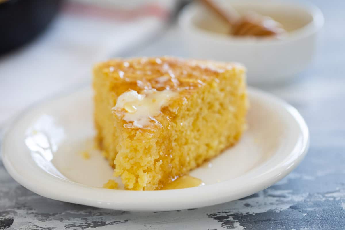Slice of cornbread topped with butter and honey.