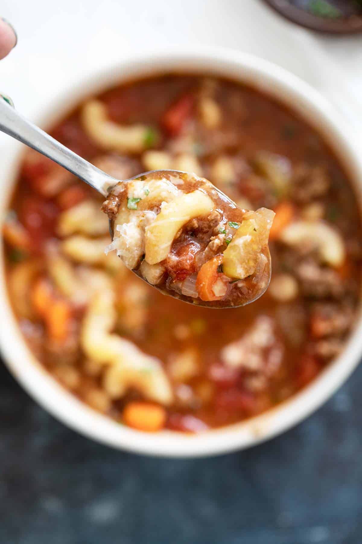 Spoonful of hamburger soup with noodles.