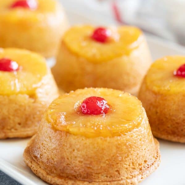 Pineapple upside down cupcakes on a tray topped with cherries.