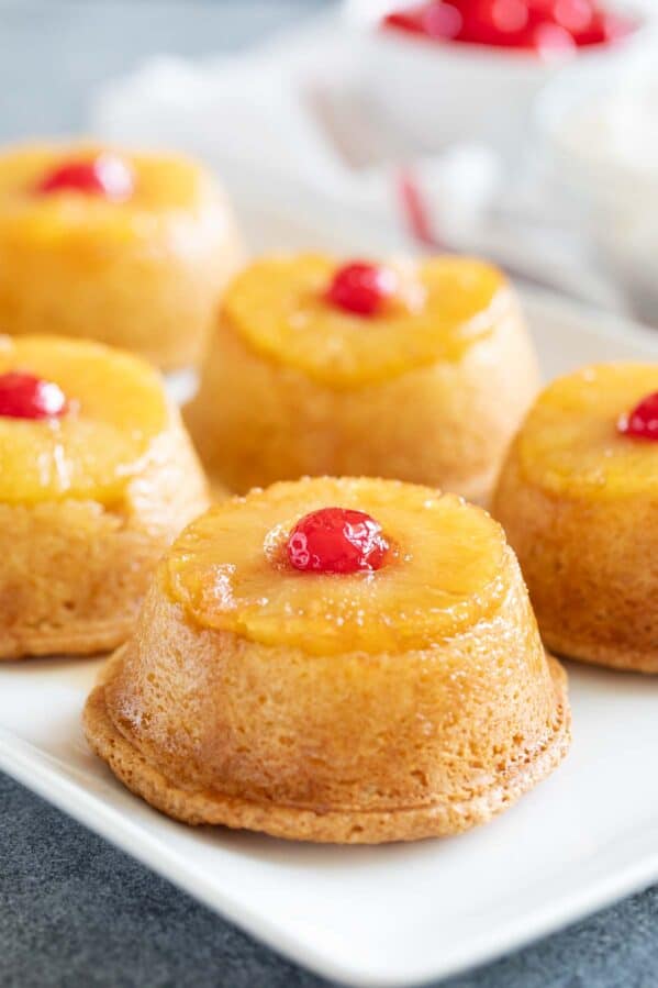 Pineapple upside down cupcakes on a tray topped with cherries.