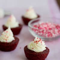 Red velvet brownie cups filled with cream cheese and topped with sprinkles.