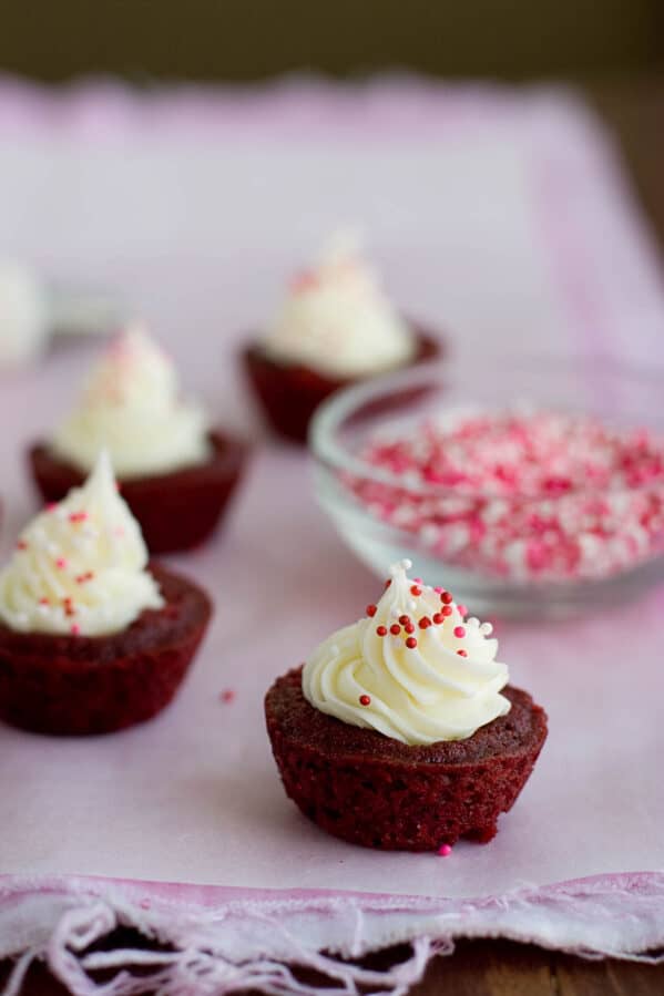 Red velvet brownie cups filled with cream cheese and topped with sprinkles.
