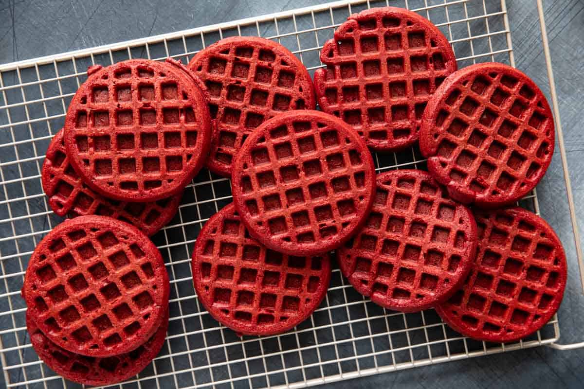 Red velvet waffles stacked on a cooling rack.