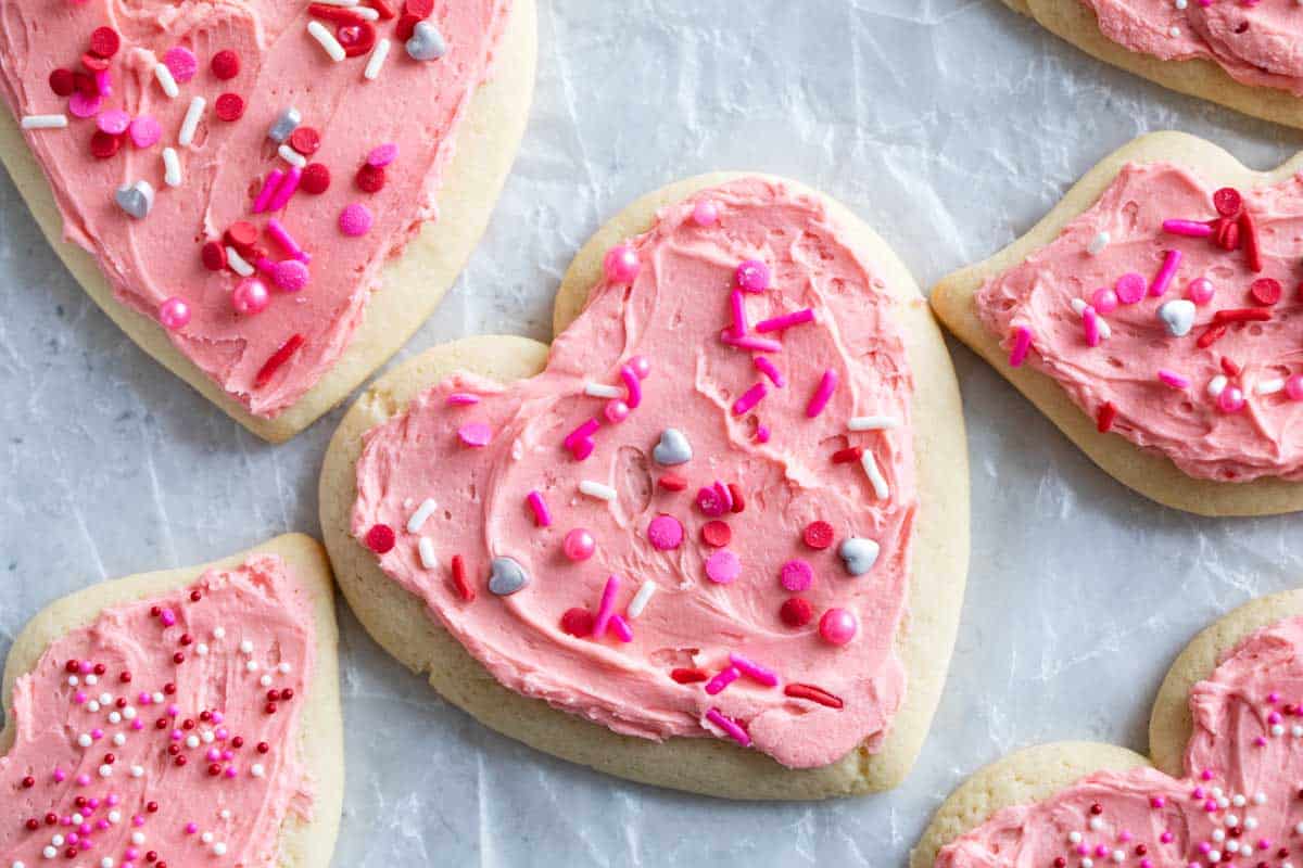 Valentine's Day Sugar Cookies shaped as hearts and lips, covered in pink buttercream.