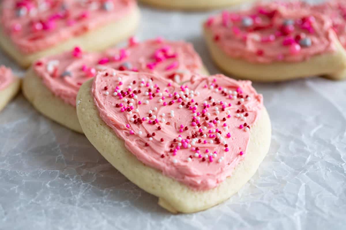 Heart shaped Valentine's Day Sugar Cookies with pink icing and sprinkles.