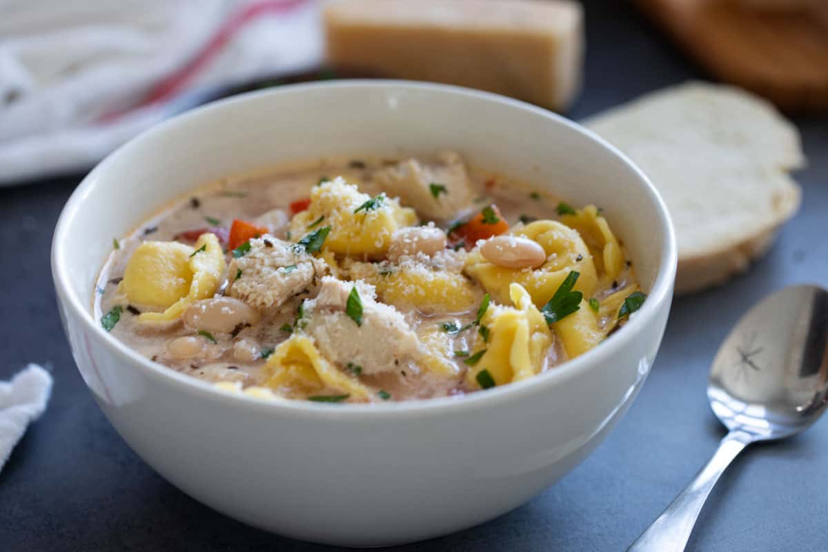 Bowl of chicken tortellini soup topped with parsley and parmesan.