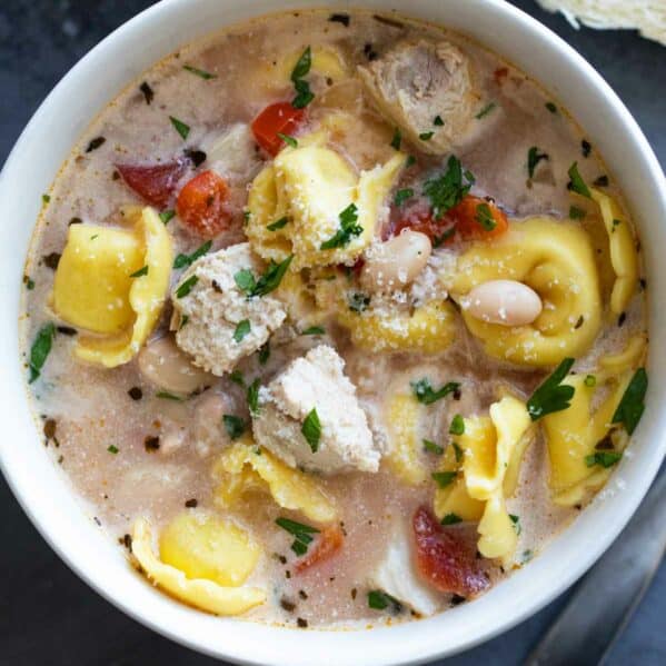 Bowl of Chicken Tortellini Soup topped with parmesan cheese.