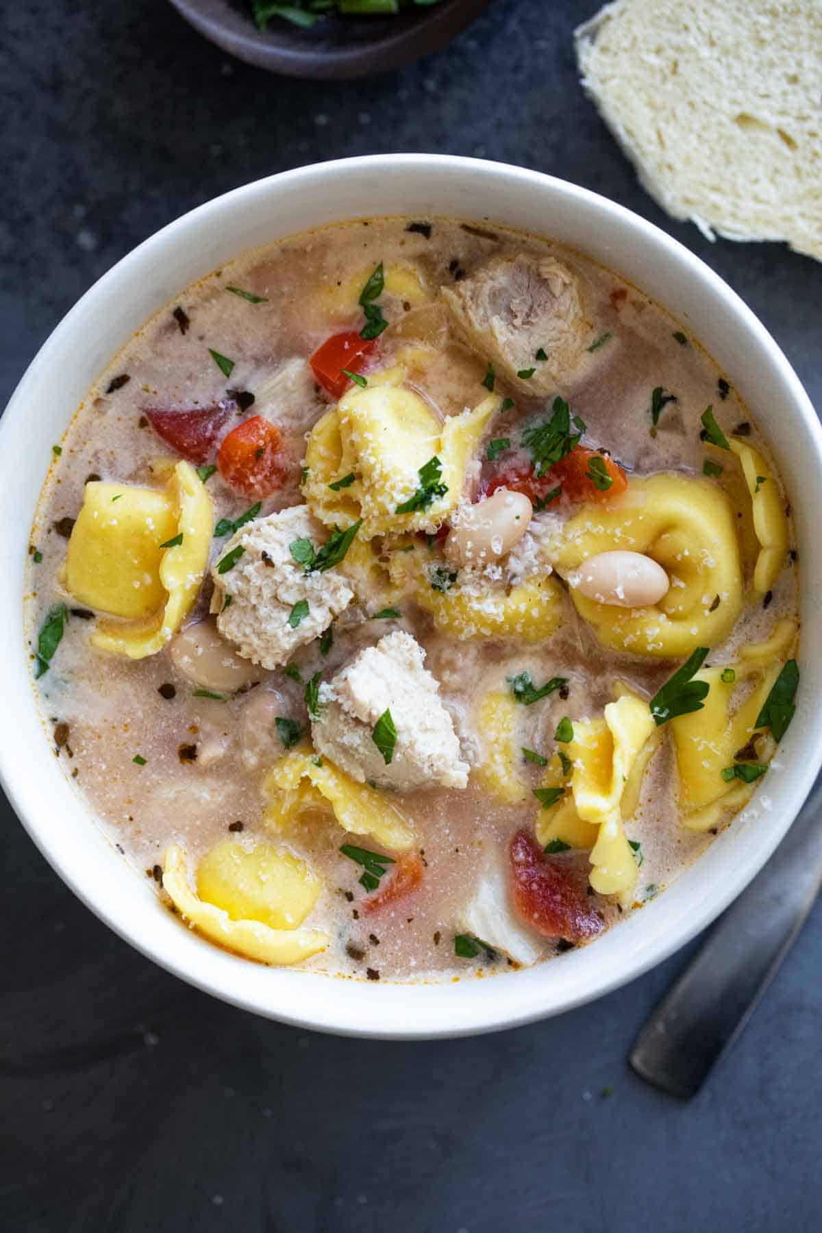 Bowl of Chicken Tortellini Soup topped with parmesan cheese.