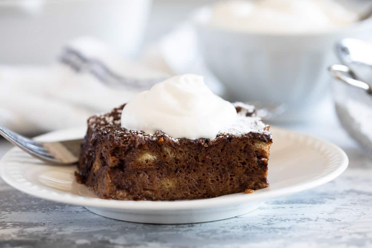 Piece of chocolate bread pudding topped with fresh whipped cream.