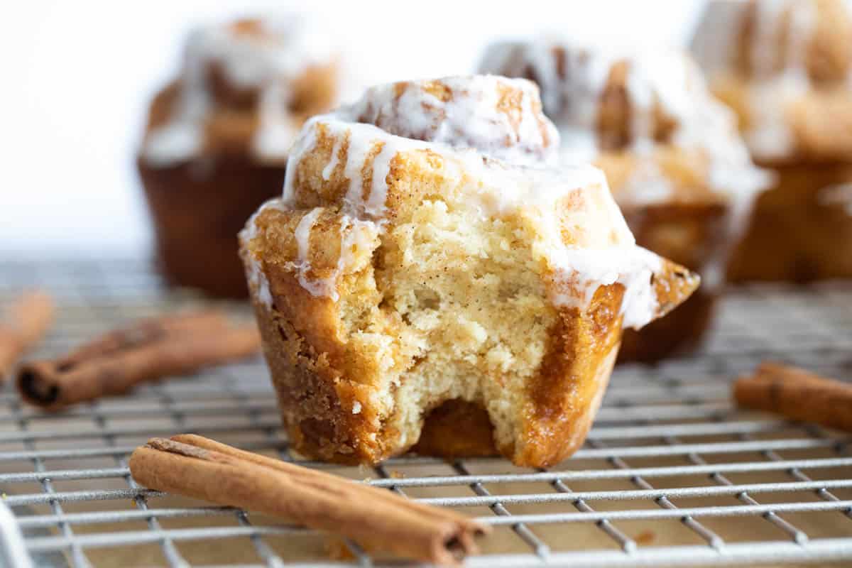 Cinnamon roll muffin with a bite taken from it.