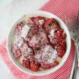 Single serving of red velvet bread pudding topped with powdered sugar.