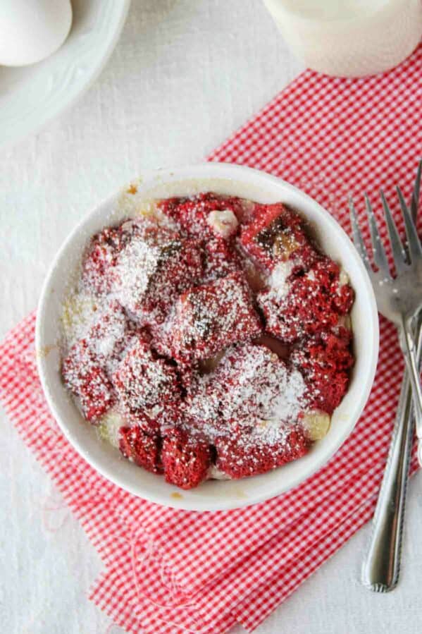 Single serving of red velvet bread pudding topped with powdered sugar.