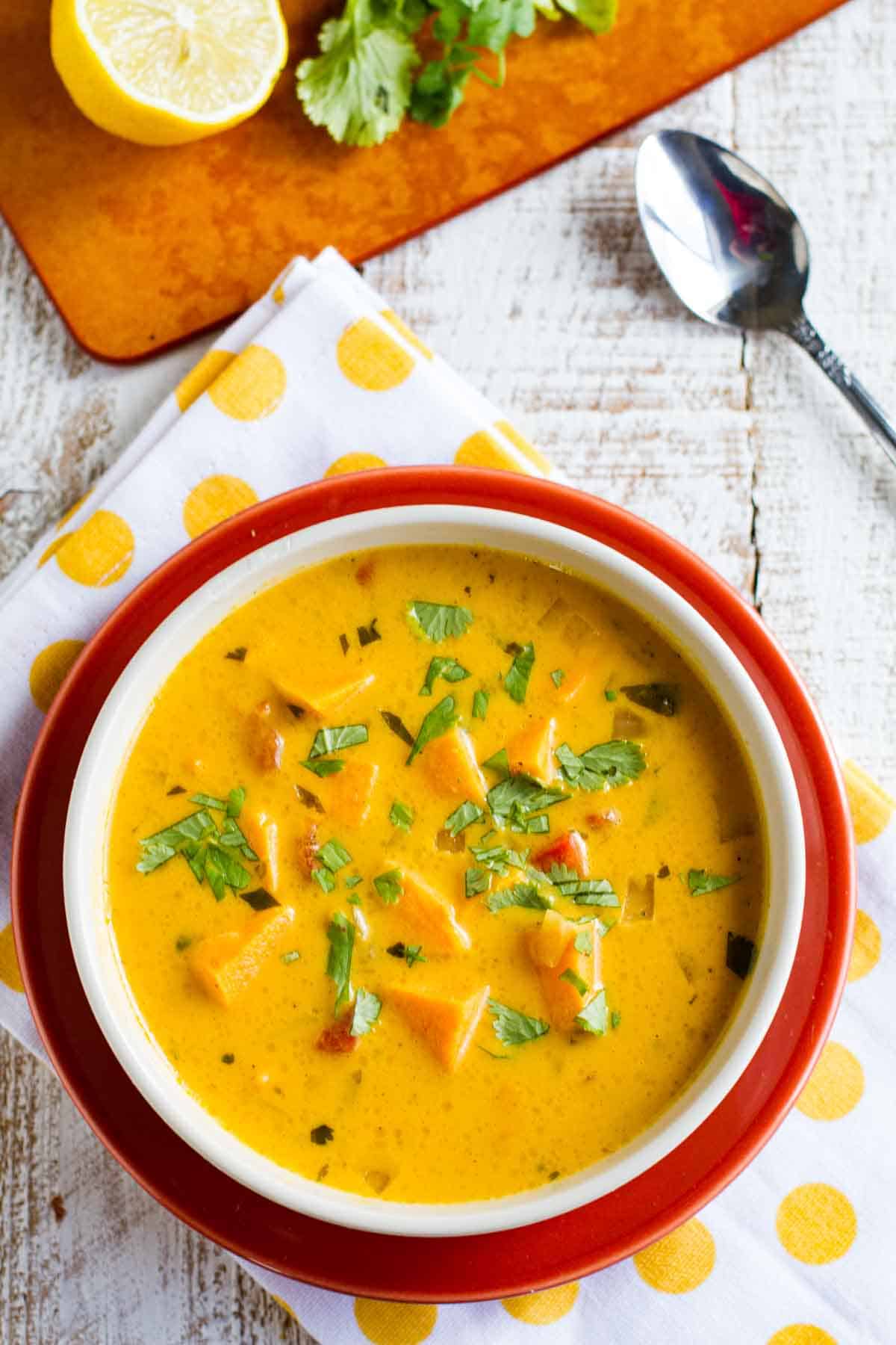 Bowl of roasted red pepper and sweet potato soup topped with cilantro.