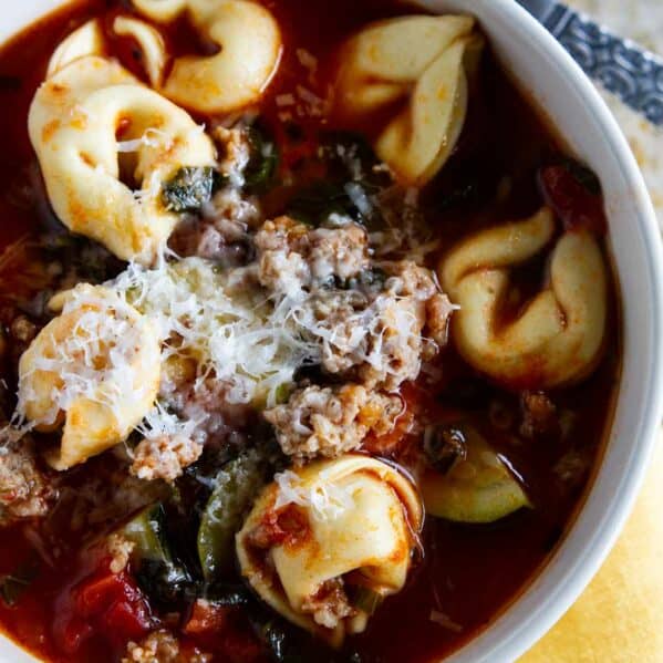Bowl of Sausage Tortellini Soup topped with parmesan cheese.