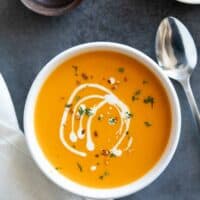 Bowl of sweet potato soup drizzled with cream.