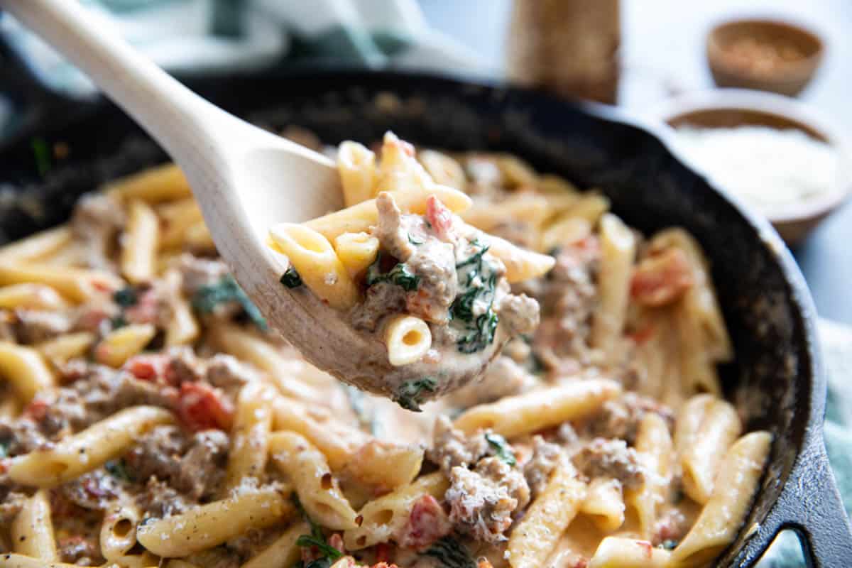 Wooden spoon filled with Tuscan pasta with sausage.