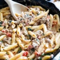 Tuscan pasta with sausage in a cast iron skillet.