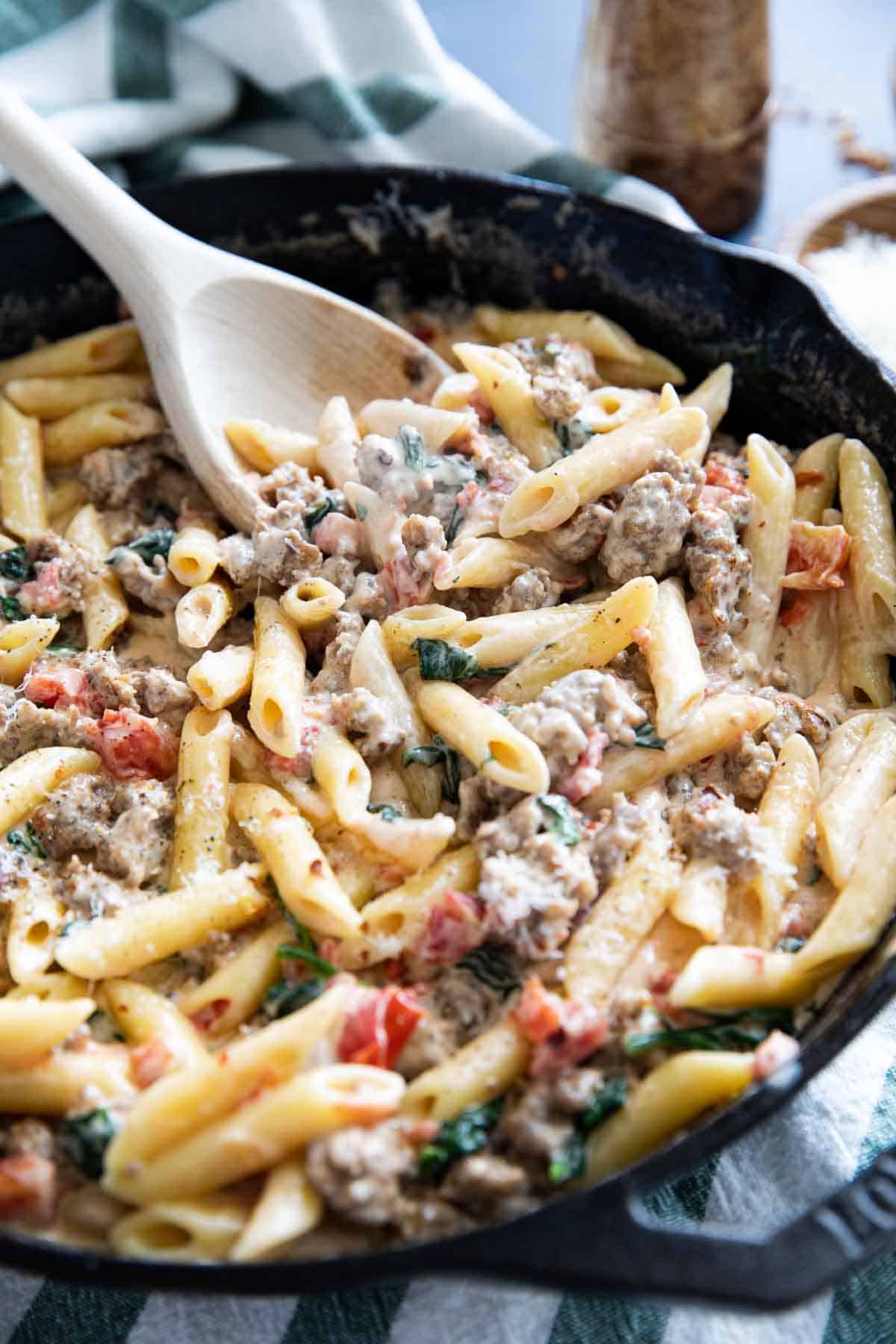 Tuscan pasta with sausage in a cast iron skillet.