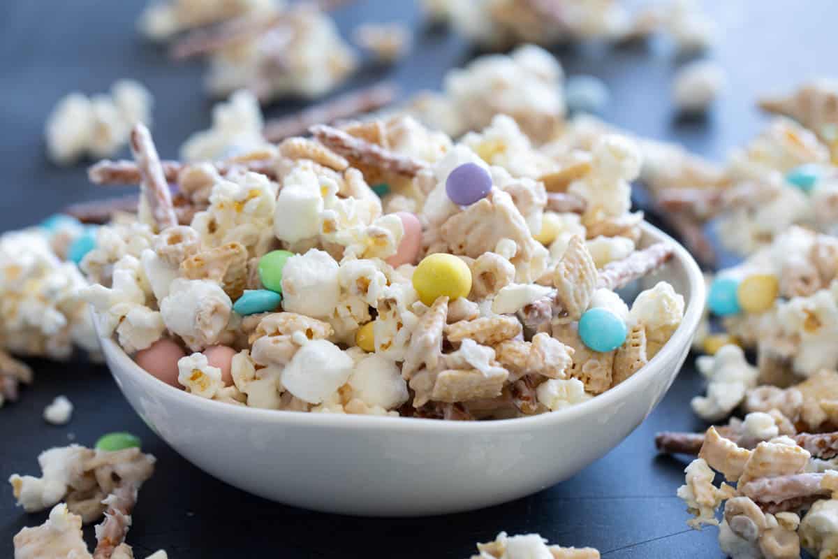 Bowl filled with Bunny Bait - cereal, pretzels, marshmallows, popcorn, and candy in white chocolate.