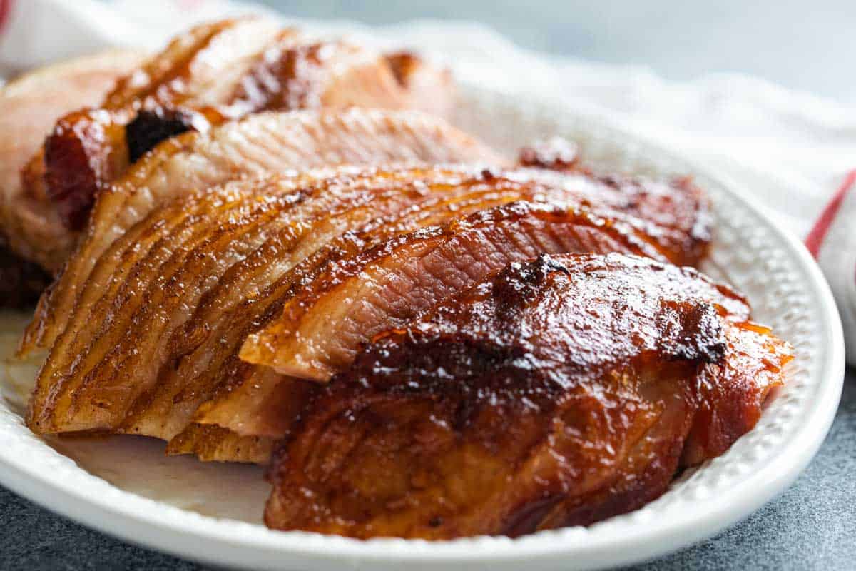This Honey Glazed Ham recipe will show you how easy it is to ditch the glaze package and make your own spice mix. So much more flavor and you know exactly what goes into it! Honey glazed ham on a platter.