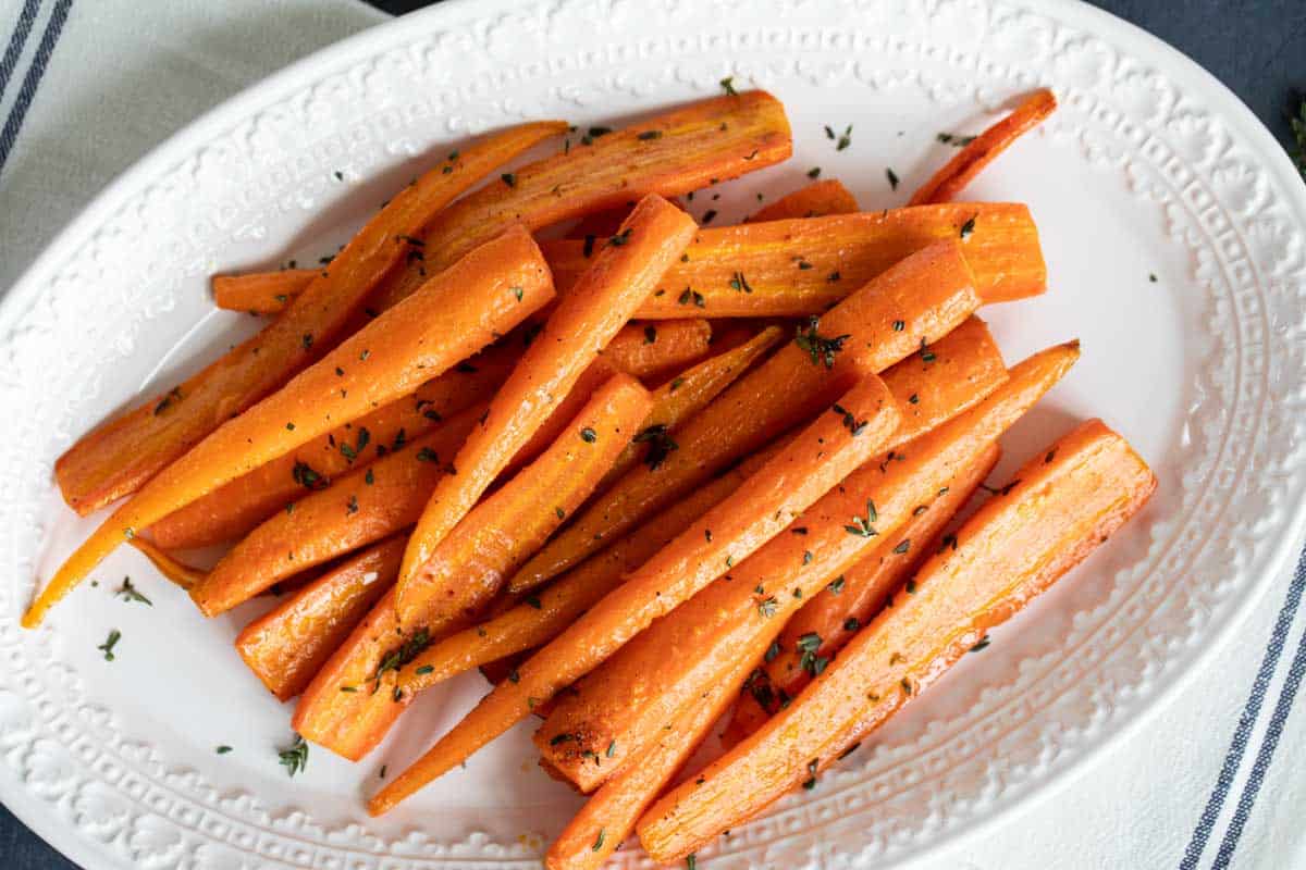 Serving dish with oven roasted carrots topped with thyme.