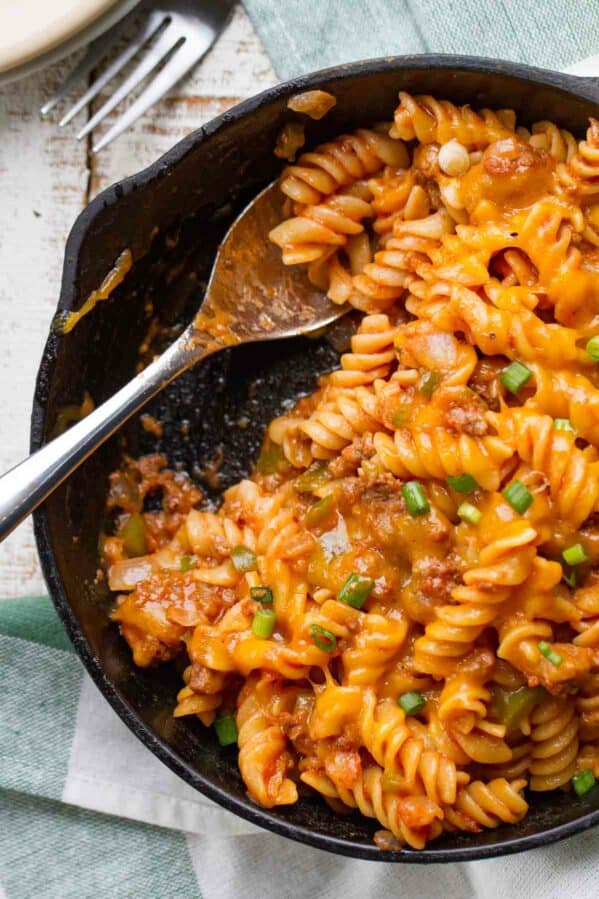 Sloppy joe pasta in a cast iron skillet with a spoon.
