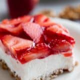 Slice of strawberry pretzel salad topped with fresh strawberries.
