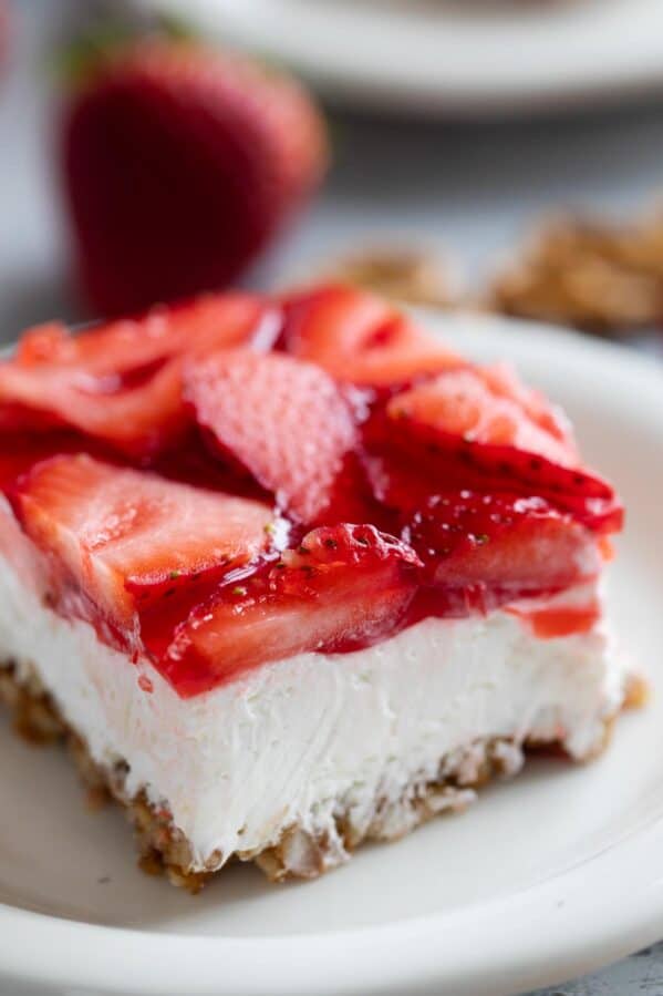 Slice of strawberry pretzel salad topped with fresh strawberries.